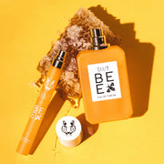 Bee 10ml Eau De Parfum travel Spray with cap removed and Bee 50ml Eau De Parfum with cap removed resting on piece of honey comb, on yellow background.
