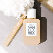 Vanilla Milk 50ml Eau De Parfum and Vanilla Milk 10ml Eau De Parfum Travel Spray on grey book next to white flower.