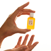 Model holding Bee 7.5ml Eau De Parfum Mini Dabber in one hand, with other hand below, on white background.